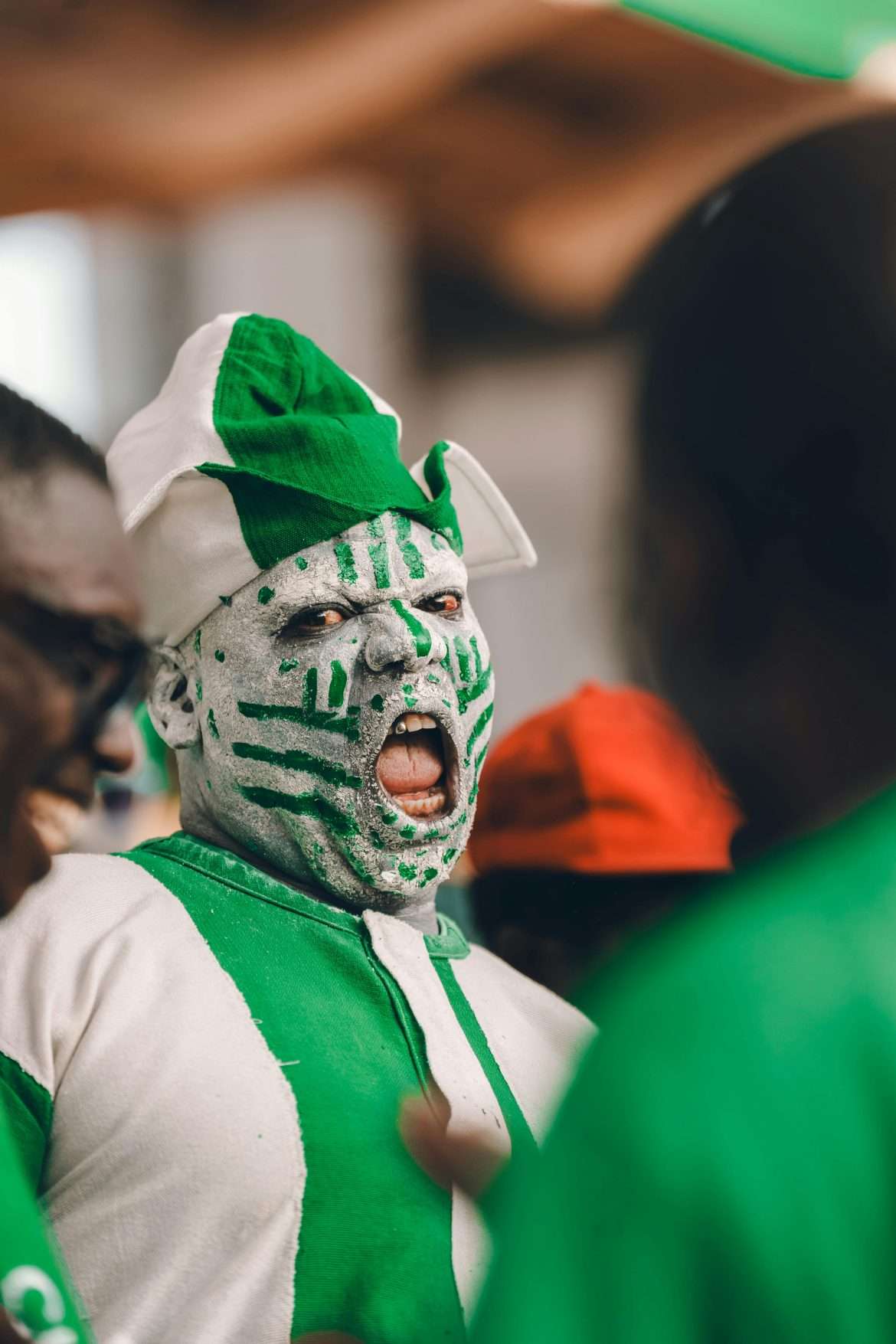 Enthusiastic Nigerian fan showcases cultural pride with green face paint and costume.