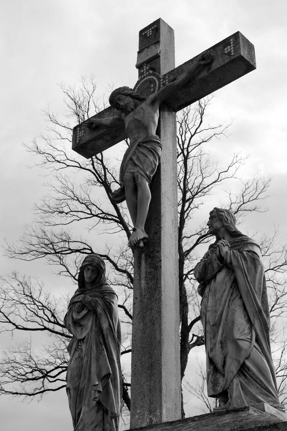 Black and white photo of a crucifixion sculpture with dramatic sky backdrop.